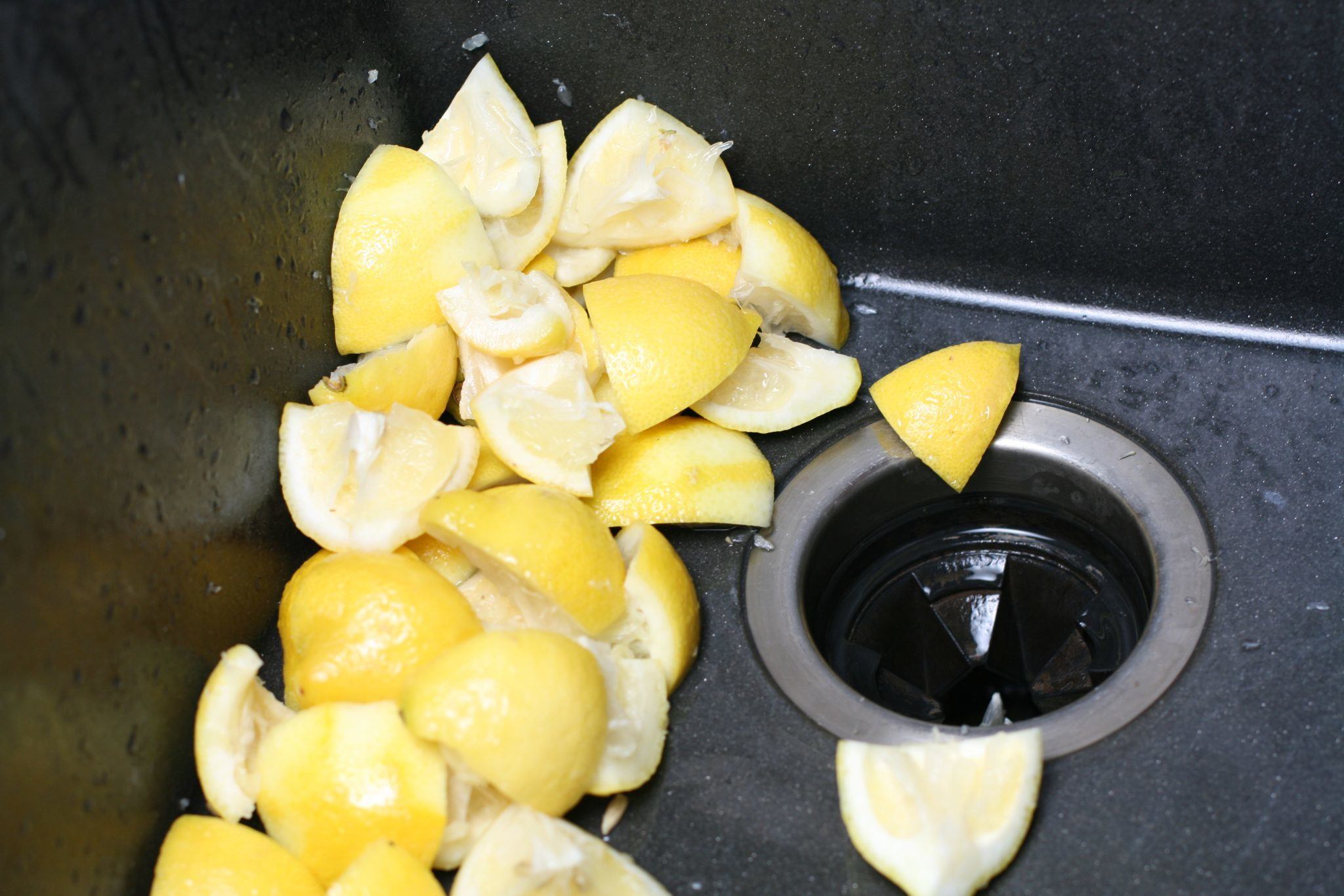 Used lemon being put inside the  garbage disposal