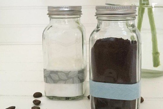 Ground coffee and baking soda inside two glass jars decorated with a colored stripe each